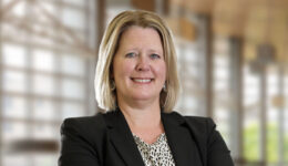Professional headshot of smiling Attorney Heidi Adair with blonde hair wearing a black blazer, neutral office background