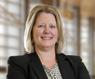Professional headshot of smiling Attorney Heidi Adair with blonde hair wearing a black blazer, neutral office background