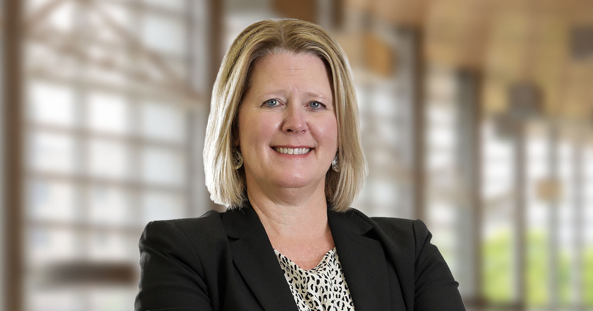 Professional headshot of smiling Attorney Heidi Adair with blonde hair wearing a black blazer, neutral office background
